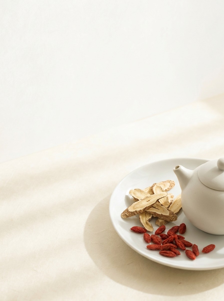 A white porcelain dish of dried astragalus slices and goji berries beside a small white teapot at the lower-right of cream rice paper, with bright empty space at the upper-left.