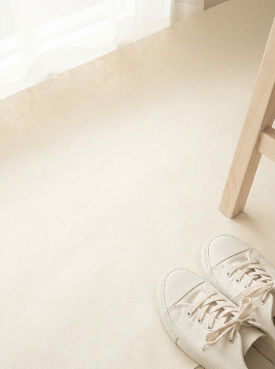 A pair of white walking sneakers beside a pale wooden chair leg pushed to the lower-right of hanji paper, the upper-left left empty.